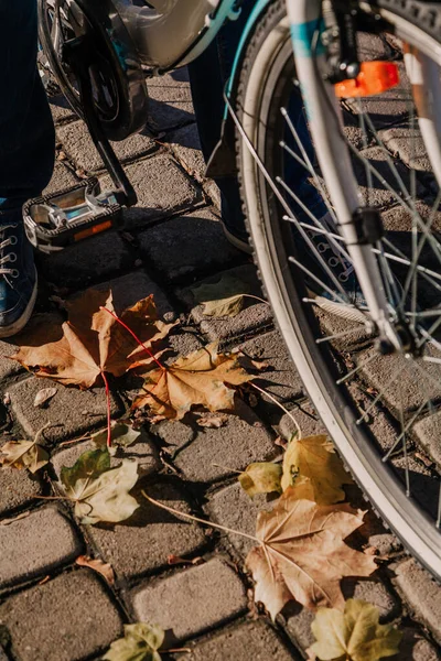 Stopa w tenisówkach stoi na jesiennym chodniku. Niedaleko rower — Zdjęcie stockowe