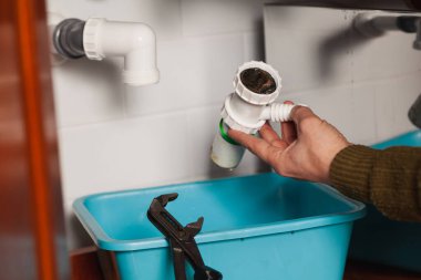 Su tesisatının elleri mutfak hidrolik deklanşör sistemini söküyor. Boru anahtarının yanında.