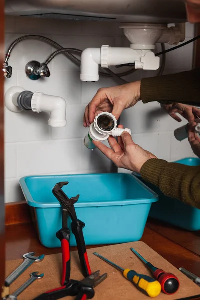 Su tesisatının elleri mutfak hidrolik deklanşör sistemini söküyor. Boru anahtarının yanında.