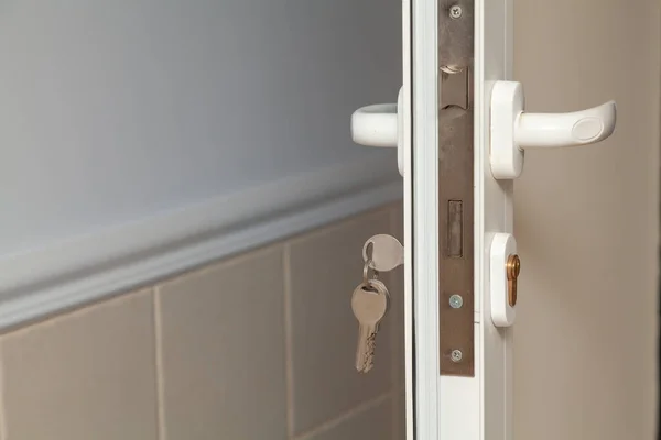 Plastic door profile. Mortise lock with two handles inside a plastic interior door. Keychain inserted on the lef