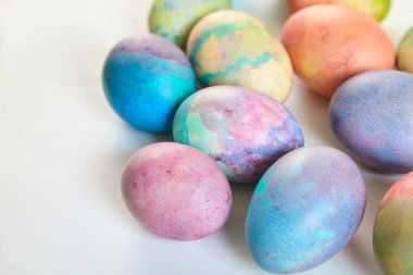 Paskalya tatiline özen göster. Farklı renklerde boyanmış birkaç tavuk yumurtası beyaz bir sırt grubunda.