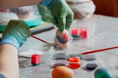 Plastik eldivenin içinde boyanmış bir Paskalya yumurtası var. Ev yapımı Paskalya yumurtası boyası evde yapılır.