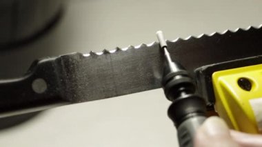 Profesyonel testere ağızlı bıçak manüel bir işçilikle döner bir aletle keskinleştiriliyor. Makro çekim