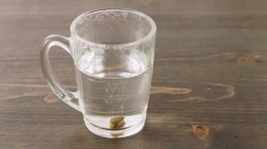 Bitkisel ilaç tabletinin sıcak suda çözünmesi. Çay kaşığıyla karıştırmak. Kendi kendine tedavi ve doğal tıp kavramı