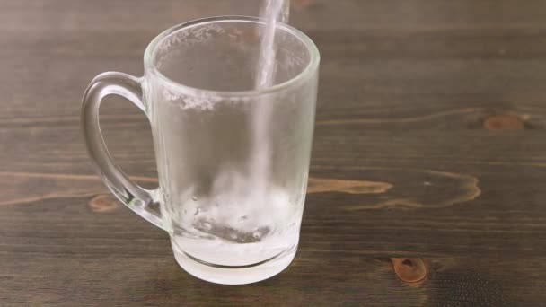 把热水倒入木制桌子上一个透明的空杯子里 蒸汽和飞溅 — 图库视频影像