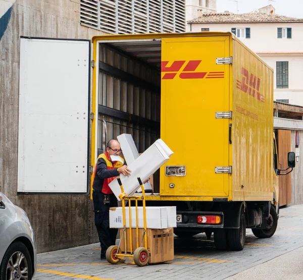 Trabajadores mayores descargan paquetes DHL del camión en la plaza central — Foto de Stock