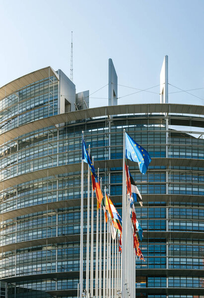 Facade of the European Parliament building in Strasbourg, France with all European Union Member States flags waving in the courtyard of the Louise Weiss building on a fine sunny spring day