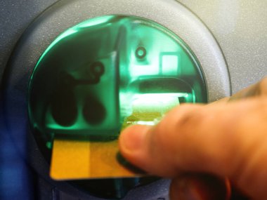 mans hand inserting a debit card into the slot of an automatic  clipart