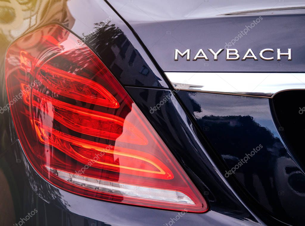 PARIS, FRANCE - MAY 21, 2018: Rear view of Maybach Mercedes logotype and red led stop light on new luxury blue Mercedes-Maybach s600 4matic awd limousine parked on street violet tones