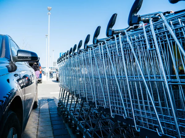 Carrinhos de compras do supermercado perto do estacionamento do carro — Fotografia de Stock