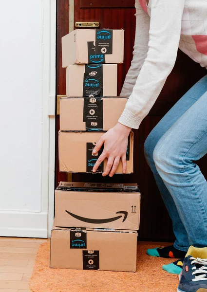 Pila de paquetes Amazon Prime entregados a una mujer de la puerta del hogar — Foto de Stock