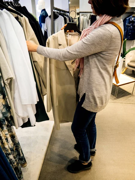 Женщина покупает красивую современную одежду в магазине повседневной одежды — стоковое фото