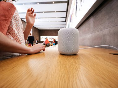 Woman testing lates Apple HomePod in Apple Store clipart
