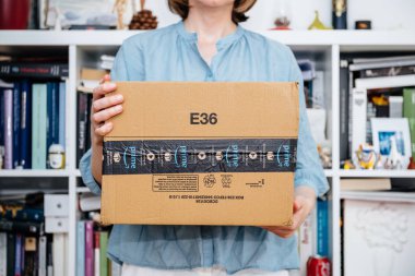 Paris, Fransa - 4 Temmuz 2018: Amazon Prime paketi teslim kitaplığı arka planda unboxing, gururlu Amazon Prime istemciyle yapmaya hazırlanıyor yeni sunu tutan kadın