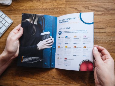 Paris, Fransa - 1 Temmuz 2018: kadın okuma reklam broşür katalog üzerinden Nespresso espresso makineleri espresso kahve kahve kapsül makineleri, ev ve profesyonel kullanım için ile demlemek