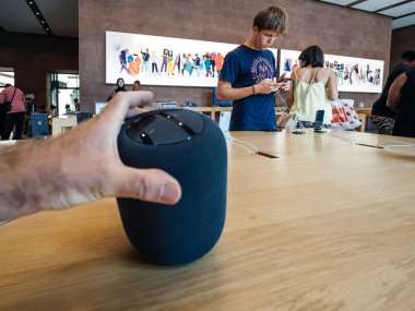 PARIS, FRANCE - JUL 16, 2018: Man hand admiring new Apple Store the latest Apple Computers HomePod smart speaker with Siri and Apple Music clipart