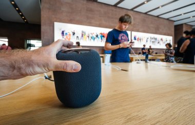 PARIS, FRANCE - JUL 16, 2018: Man admiring new Apple Store the latest Apple Computers HomePod smart speaker with Siri and Apple Music clipart