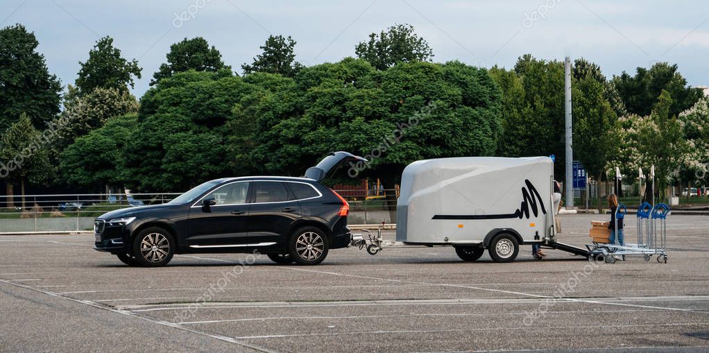 STOCKHOLM, SWEDEN - JUN 7, 2018: Wide image of single mother with her daughter loading  in the car trailer good bought from IKEA furniture store in the wide empty parked of the Swedish furnitur