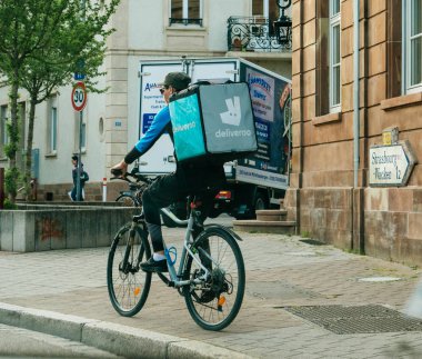 Strasbourg, Fransa - 18 Mayıs 2018: Hızlı Deliveroo bisikletçi müşteri taze ve sıcak yemek ile ulaşmak için hızlı sokakta sürüş farklı çantalı