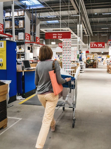 Mulher empurrando móveis carrinho de compras Ikea — Fotografia de Stock