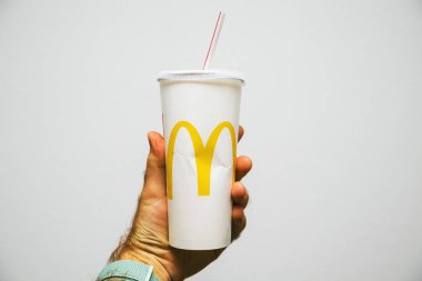 Paris, Fransa - 27 Temmuz 2018: beyaz arka planı Mcdonalds Cola dünyanın birinin yakınında sarı logosu ile plastik saman ile bir fincan en büyük fast food restoranlar tutan adam