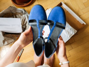 Woman holding pair of new blue elegant shoes right after unboxing - POV point of view admiring the merchandise shopping online clipart