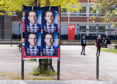 STRASBOURG, FRANCE - MAY 5, 2018: Emmanuel Macron, candidate to the Presidency of France poster on a dedicated campaign agitation area in front of French School Lyceum kids clipart