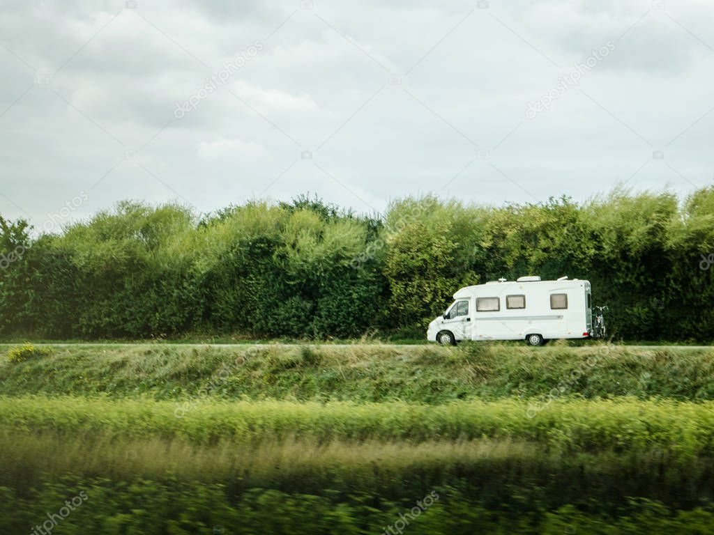 Fast RV camer van driving on the green dunes in Netheralnds during Euroeapn holidays - drive to the left
