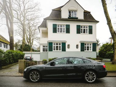 Hamburg, Almanya - 21 Mar 2018: Siyah Audi A8 ikinci el araba yan görünüm karşı yeşil çim ile küçük beyaz ev yolda park halinde