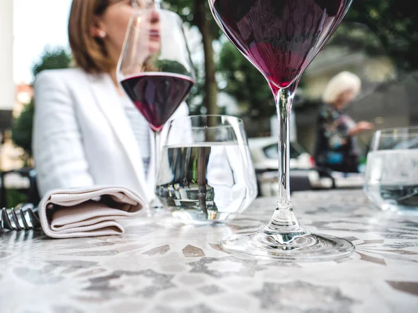 Verres à vin en cristal sur la table au restaurant femme boire — Photo