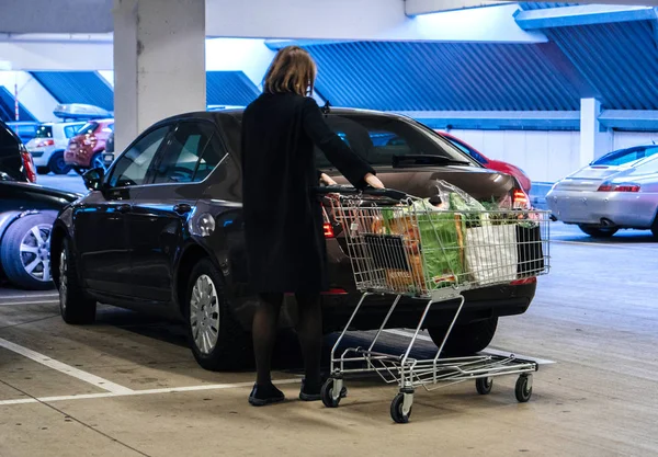 Mujer con carrito de la compra supermercado en el aparcamiento — Foto de Stock