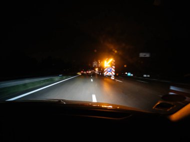 Yolda yol işaretleri ve güvenlik trafik ışıklı ok bulanık ışıkları ile gece zamanında kamyona kaza veya yol çalışmaları sırasında sürüş araba içinde ateş