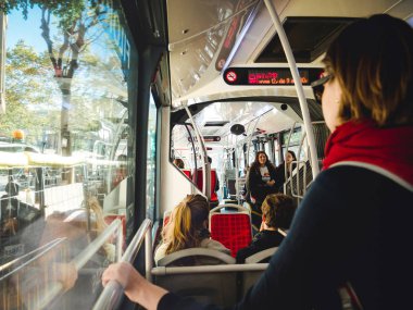 Barcelona, İspanya - 12 Kasım 2018: Barselona halk otobüsü ile commuters yolcu otobüs terminalinde çıkmak hazırlanıyor arka planda süre commuting gidon tutan kadın