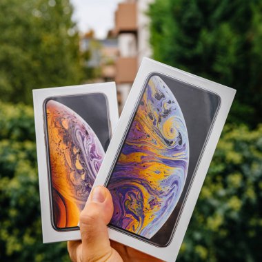 PARIS, FRANCE - SEP 21, 2018: Proud man customer POV comparing the new latest iPhone Xs and Xs Max smartphones telephones before the unboxing against green background clipart
