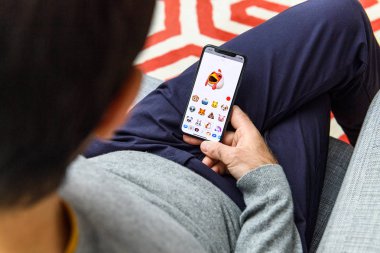 LONDON, UK - SEP 21, 2018: Man using the new singing chicken AR Memoji emoji face on Apple iPhone Xs with the immense OLED retina display and a12 bionic chip clipart