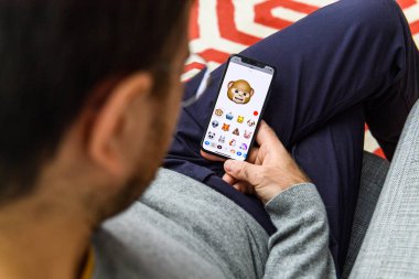 LONDON, UK - SEP 21, 2018: Man using the new AR Memoji emoji on Apple iPhone Xs with the immense OLED retina display and a12 bionic chip, with the face of mokey clipart