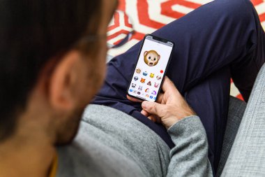 LONDON, UK - SEP 21, 2018: Man using the new wow AR Memoji emoji on Apple iPhone Xs with the immense OLED retina display and a12 bionic chip, with the face of mokey clipart