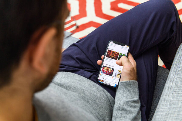 LONDON, UK - SEP 21, 2018: Man using the new Apple iPhone Xs with the immense OLED retina display and a12 bionic chip, looking over the app application Tripadvisor app