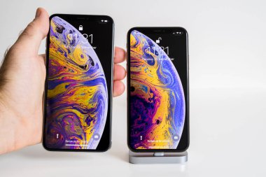 Paris, Fransa - 25 Eylül, 2018: Erkek el karşılaştırmak yeni iphone Xs ve Xs Max smartphone modeli Apple bilgisayarlar tarafından yakın çekim ile ana ekran cihaz ve sıvı duvar kağıdı unlocking önce