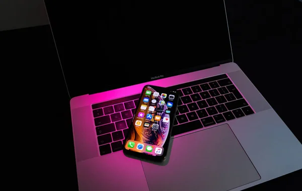 2018年9月25日 Iphone 最大的智能手机模型由苹果电脑关闭 最新的金色苹果 Iphone 上粉红色的洋红色光在 Macbook Pro Laptopkeyboard — 图库照片