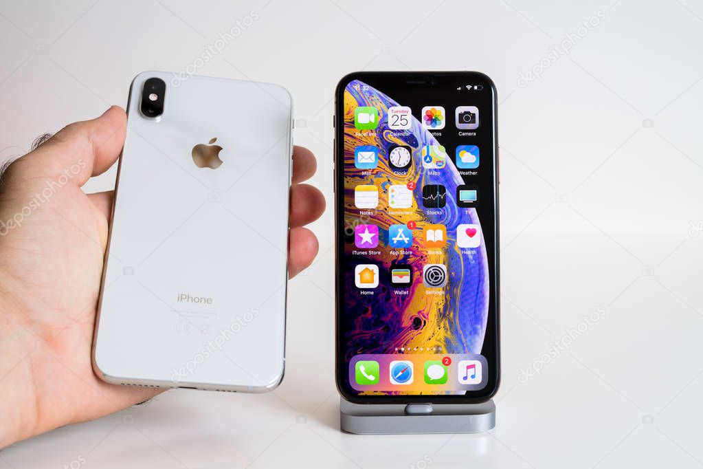 PARIS, FRANCE - SEP 25, 2018: Male hand compare new iPhone Xs and Xs Max smartphone model by Apple Computers close up with man holding the white one