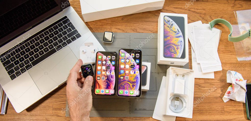PARIS, FRANCE - SEP 24, 2018: Unboxing of iPhone Xs and iphone Xs Max together with Apple Watch Series 4 on a computer table in geek room - latest Apple computers announced devices