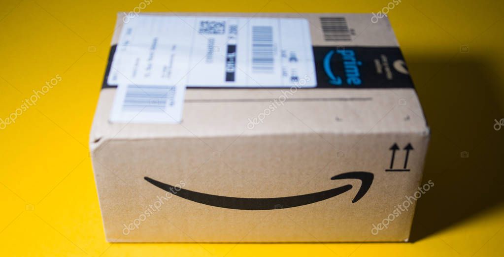 PARIS, FRANCE - SEP 28, 2018: Front view of new Amazon Cardboard box against yellow background smile log- tilt-shift lens