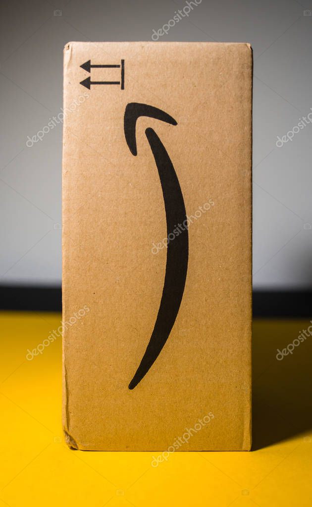 PARIS, FRANCE - SEP 28, 2018: New Amazon Cardboard box in vertical position against yellow background. Amazon Prime is the online paid subscription service offered by Amazon.com web-commerce site