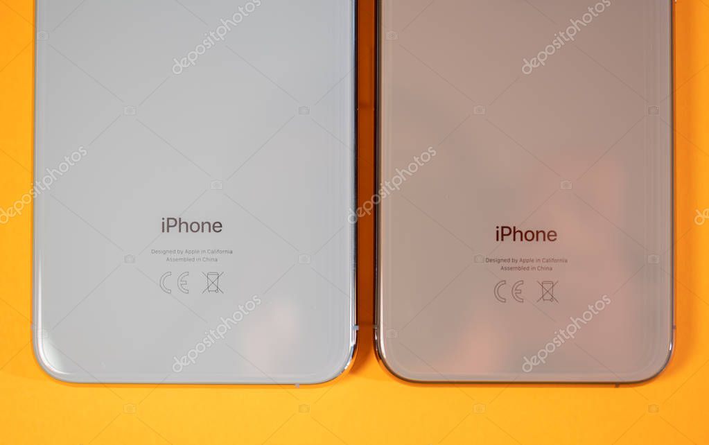 PARIS, FRANCE - SEP 27, 2018: Apple Computers iPhone Xs and Xs Max as hero object on bright glamorous modern neon pop orange background - smartphone telephone with OLED display rear glass logo