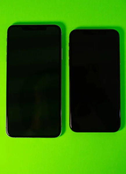 Due Apple iPhone Xs Max sullo sfondo verde vibrante — Foto Stock