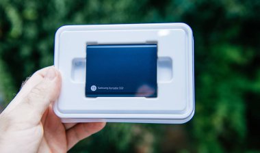 Paris, Fransa - 14 Ağustos 2018: Samsung T5 taşınabilir Ssd 2 tb harici sabit disk disk yüksek okumak ve yazmak hız yeşil arka plan unboxing testi karşı-ile mavi renk tutan adam el