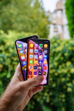 Paris, Fransa - 2 Ekim 2018: Gururlu adam müşteri karşılaştırıldığında yeni en son iphone Xs ve Xs Max smartphones Pov yeşil açık şehir arka planı unboxing sonra telefonlar