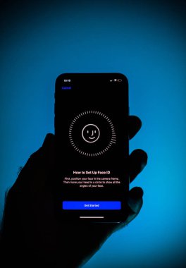 PARIS, FRANCE - OCT 2, 2018: How to set up FaceId on message on display of new Apple iPhone Xs smartphone with Face ID virtual facial recognition function - against blue background clipart