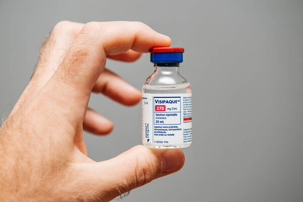 PARIS, FRANCE - OCT 2, 2018: Doctor holding Visipaque - Iodixanol package containing the contrast agent for the medical intervention under CT scanner on doctors table - iodine-containing non-ionic